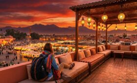 Solo traveler relaxing on a Marrakech hostel rooftop with medina views during AFCON excitement, best hostels in Marrakech for solo travelers offering affordable social stays in Morocco's vibrant culture, colorful souks and sunset skies