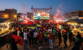 Excited crowd at AFCON fan zones Morocco watching Gabon vs. Ivory Coast match in Jemaa El-Fna Square, Marrakech, blending football thrill with New Year's Eve celebrations, vibrant public viewing experience for ticketless fans