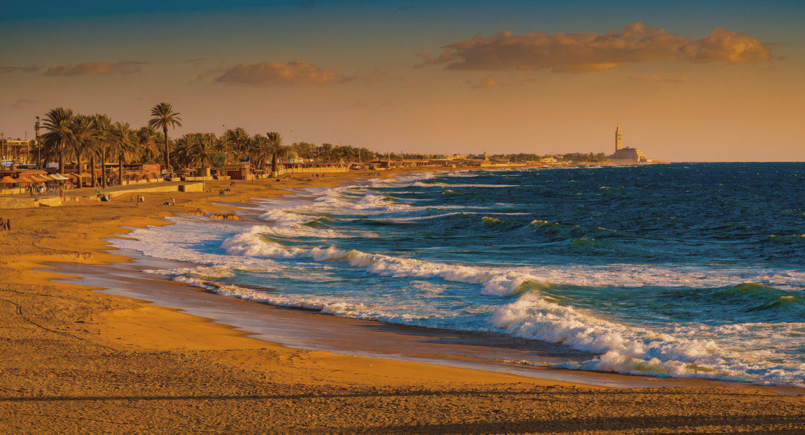 Panoramic view of Ain Diab urban beach along Casablanca Morocco coastline at golden hour, with Atlantic waves and city skyline, showcasing the best Casablanca Morocco beach experience