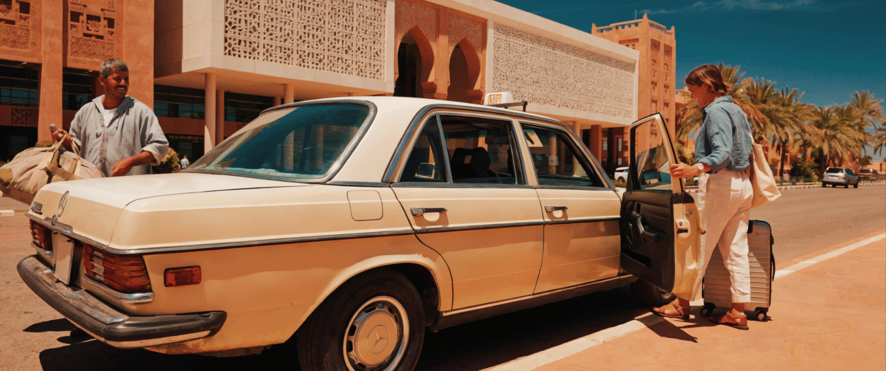 A classic beige Mercedes taxi waiting outside Marrakech Menara Airport terminal for arriving passengers.