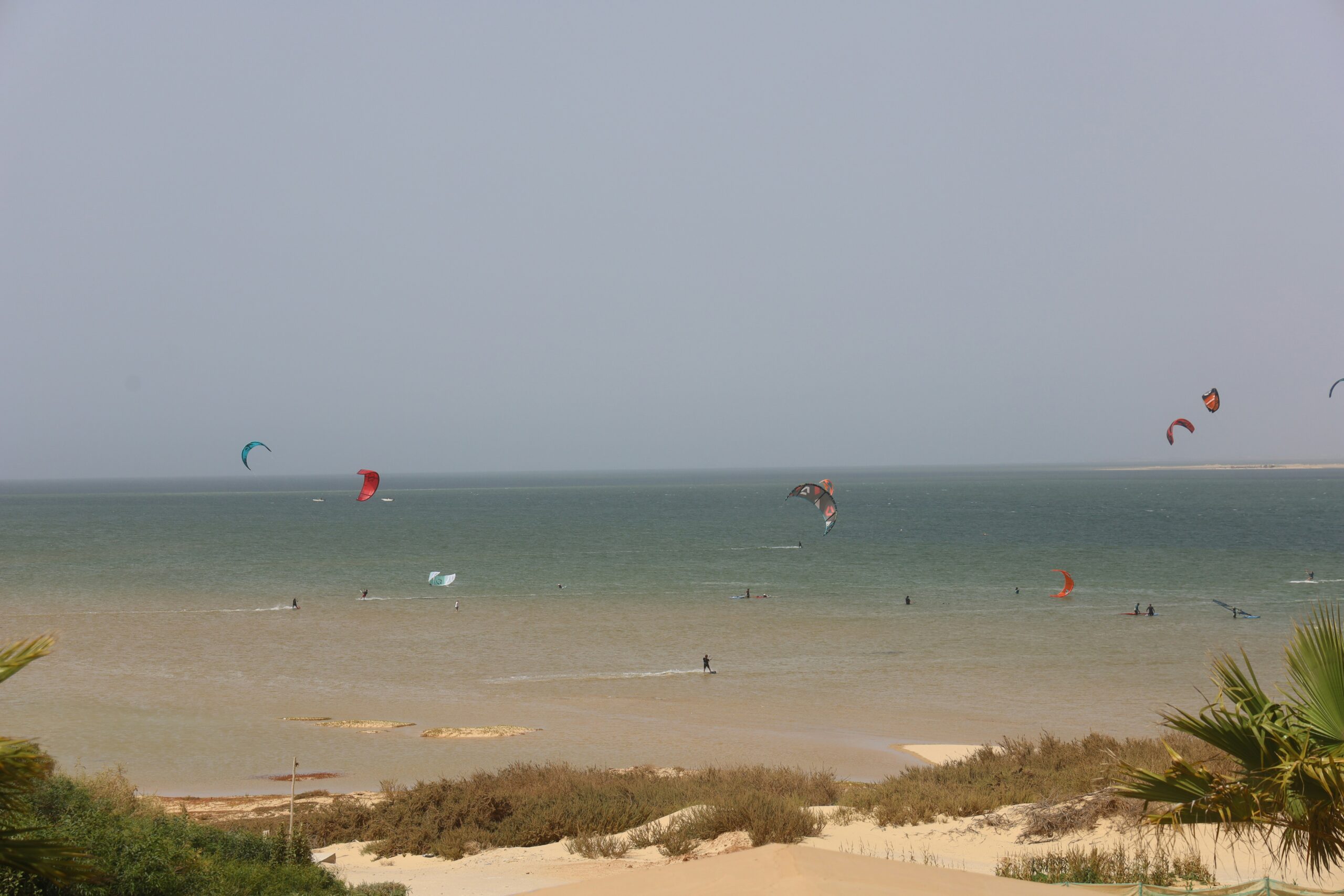 Kitesurfers on the flat turquoise lagoon at Dakhla Morocco under a clear sky