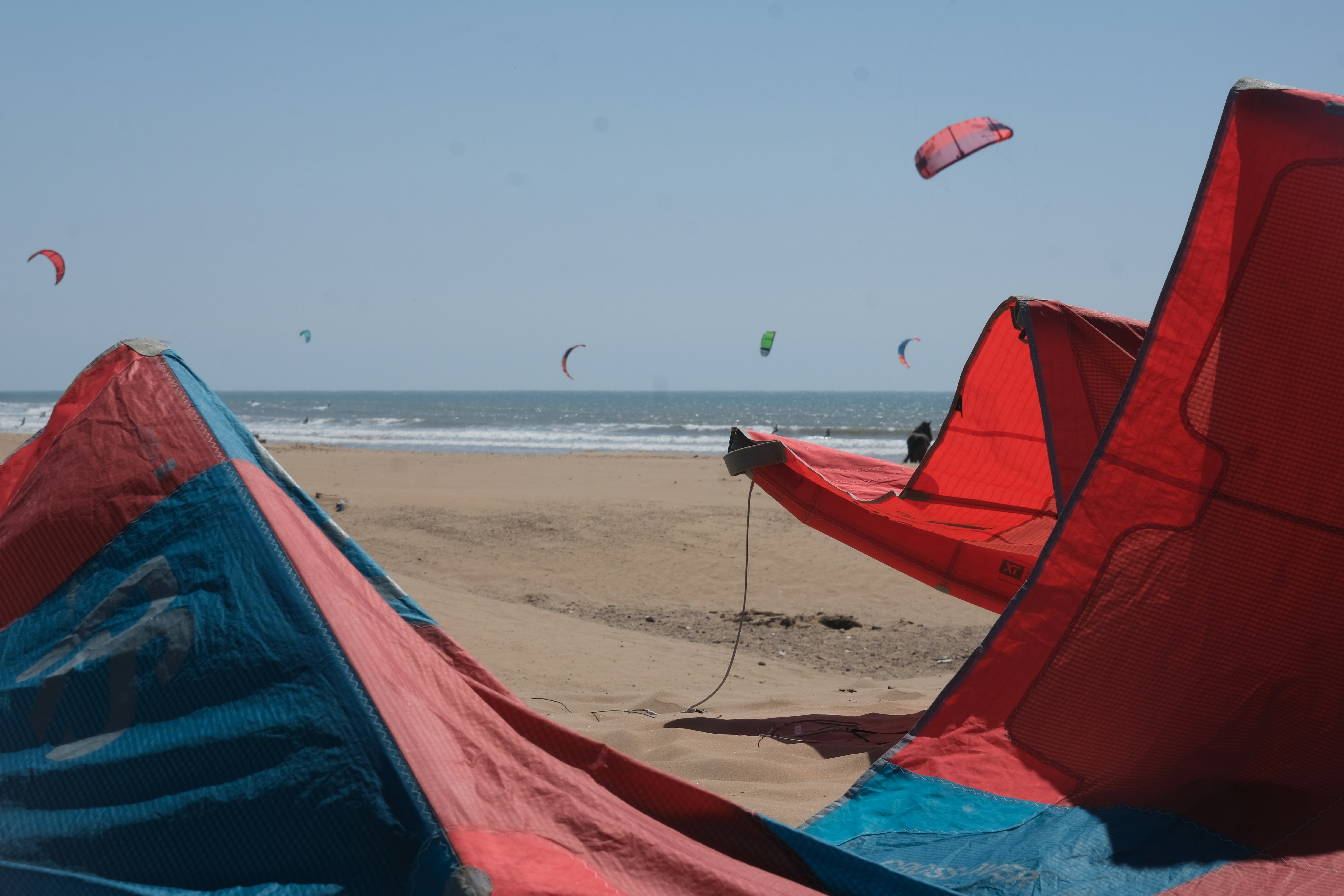 Kitesurfers and windsurfers on Essaouira beach with colourful kites against the Atlantic sky
