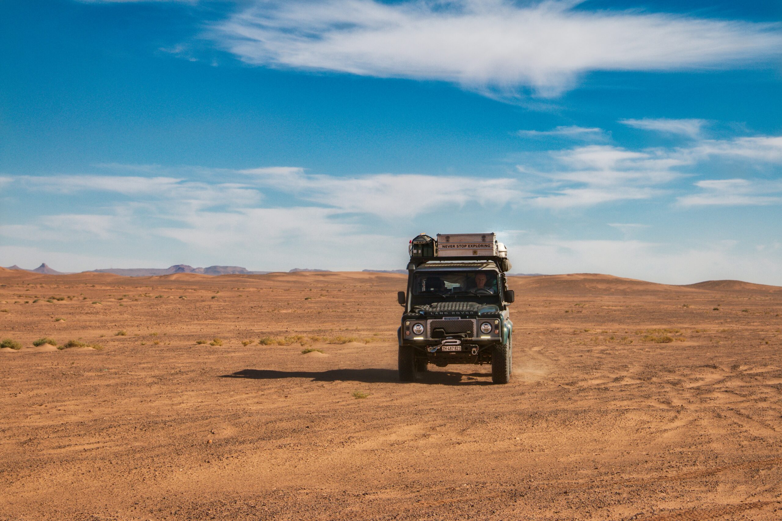 A green truck driving across a desert landscape, Laâyoune