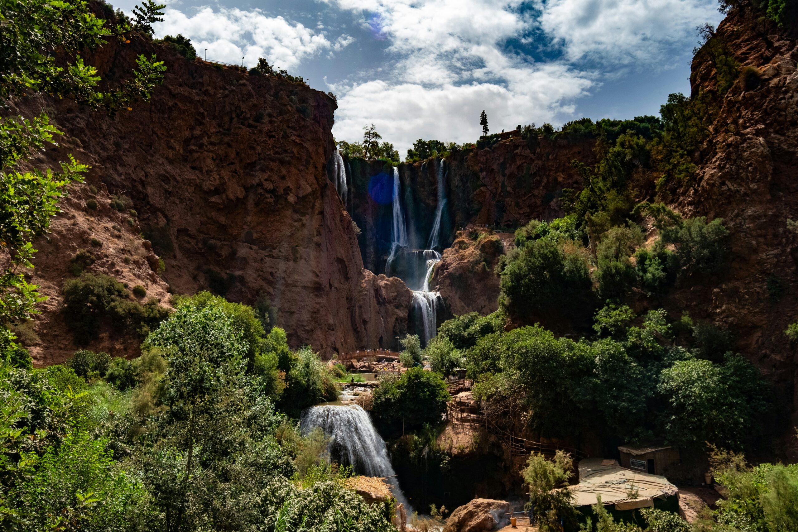 A picturesque waterfall surrounded by lush greenery, with a rocky cliff nearby, Béni Mellal-Khénifra Ouzoud